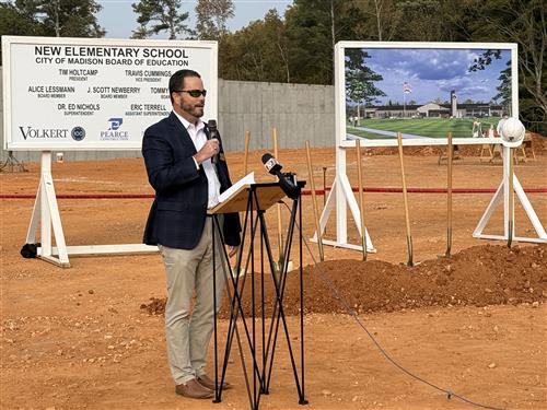 Tim Holtcamp at podium in front of rendering of the new elementary school